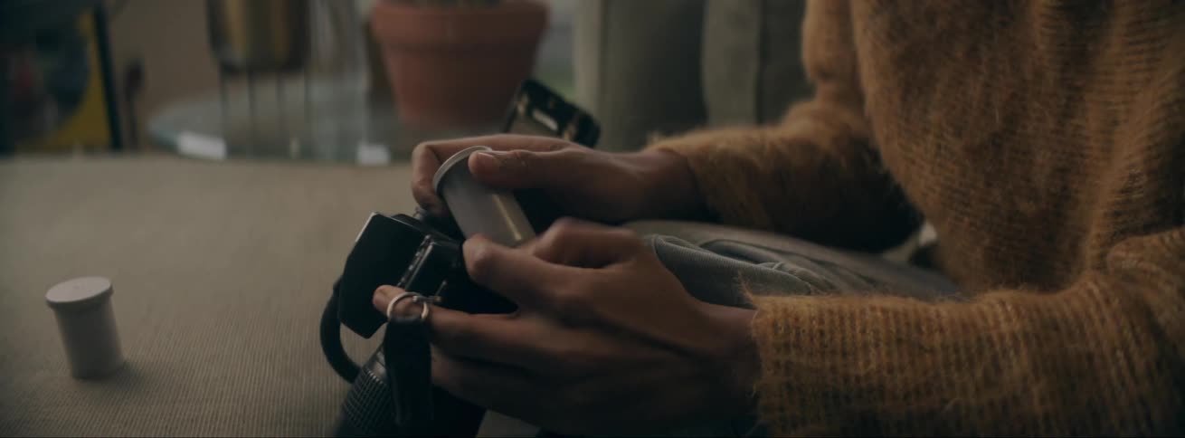 Black woman sitting in the couch handling her photographic camera