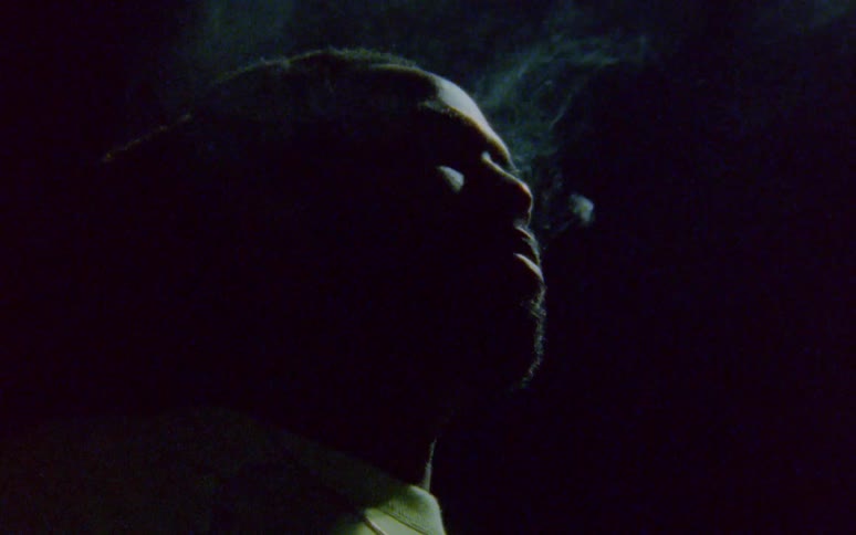 A person smokes a cigarette and exhales the smoke out