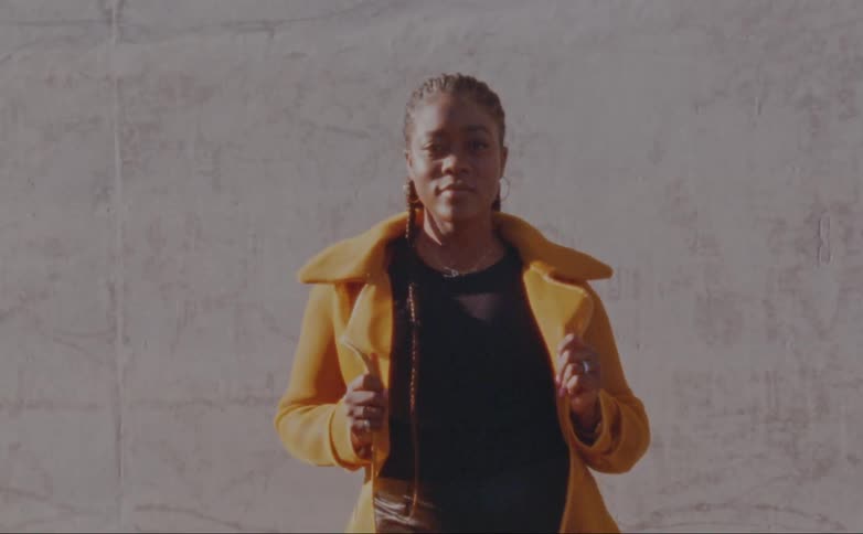 Woman with dreadlocks yellow jacket and black t shirt poses for the camera