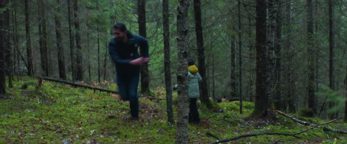 A man and boy play around in the forest