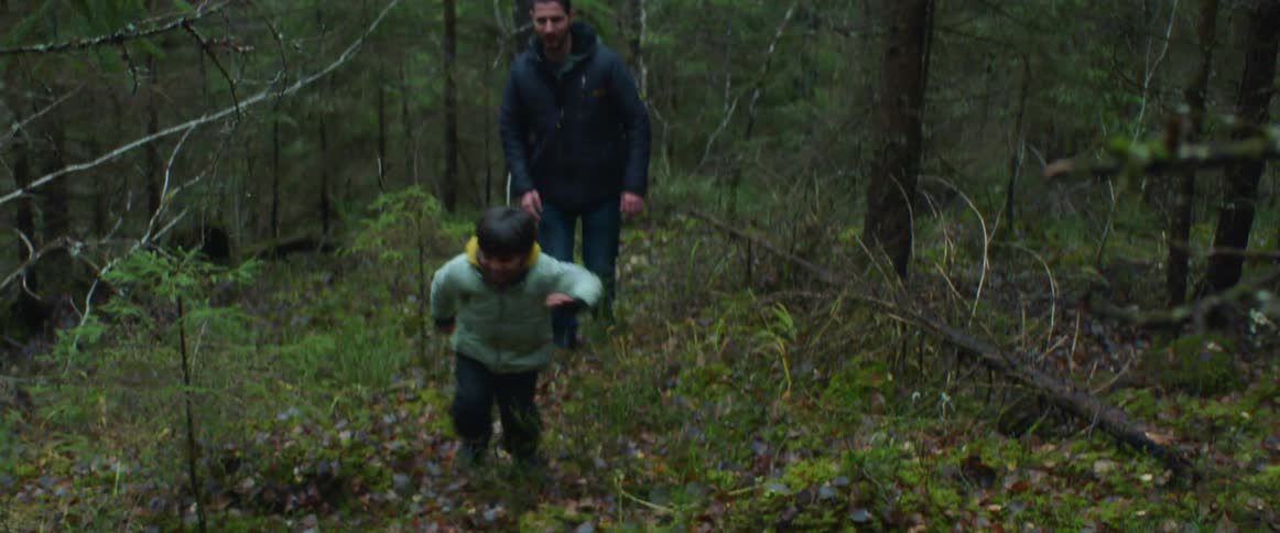 A man chases after his boy in the forest
