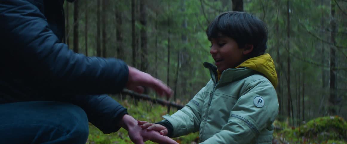 A boy is playing with a man in the forest