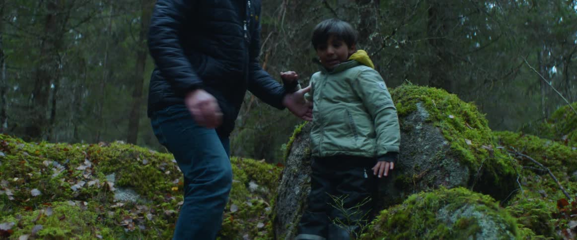 A man lifts a child from the rocks