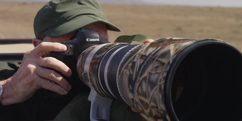 A man is using a long lens to take photographs