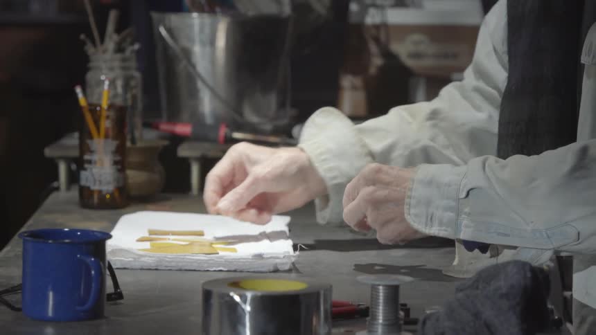 A man placing a glass shard on a workbench