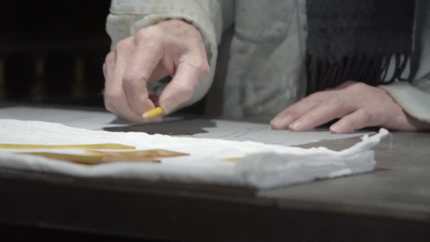 A man using a pencil to measure something written on a piece of paper