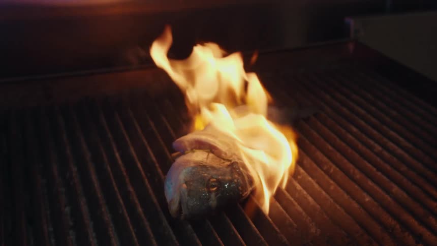 A fish on a grill is in flames