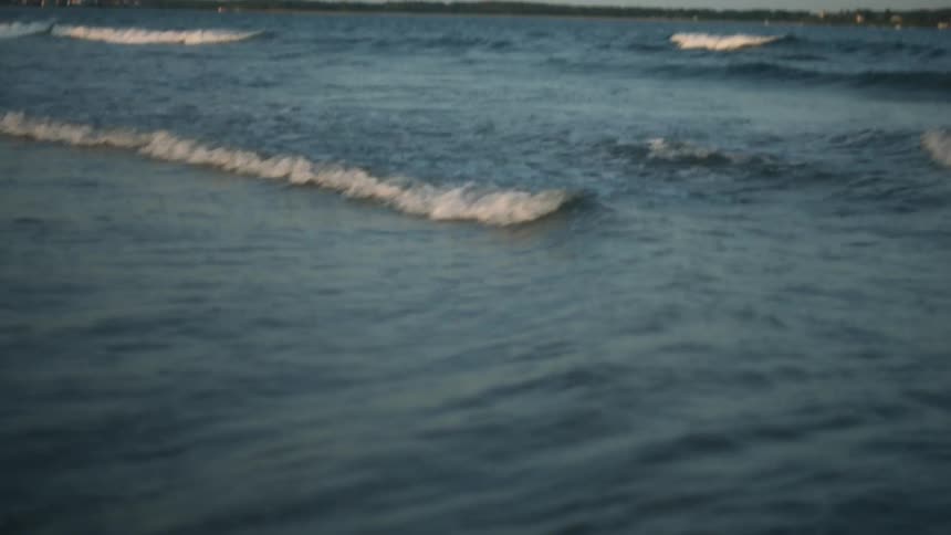 Ocean waves roll in to shore as mountains sit in the distance