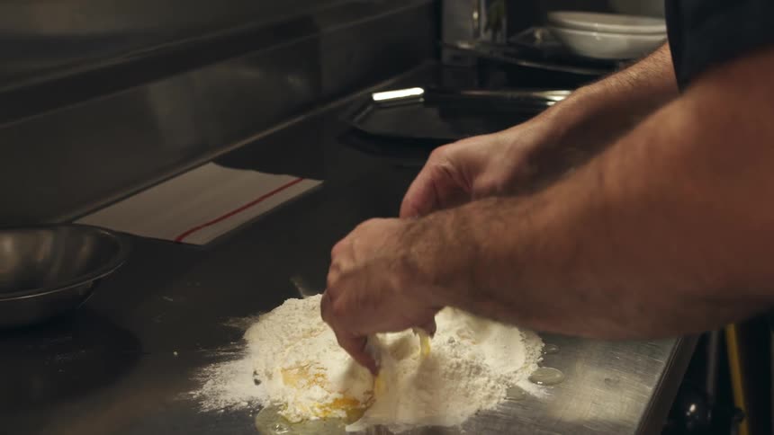 A chef combines flour and egg in the kitchen