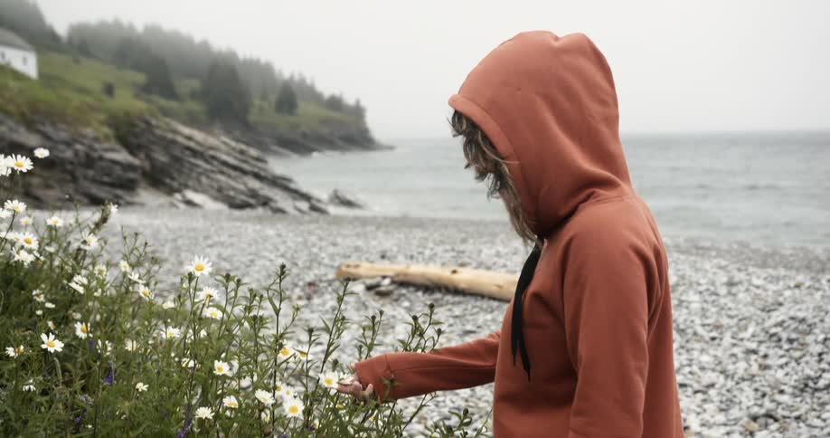 A woman is touching the flowers on the beach