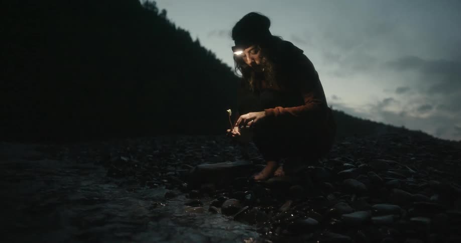 A camper brushes her teeth in a river