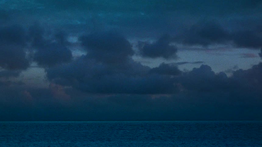 Beacon blinks on shore under clouds some tinted red