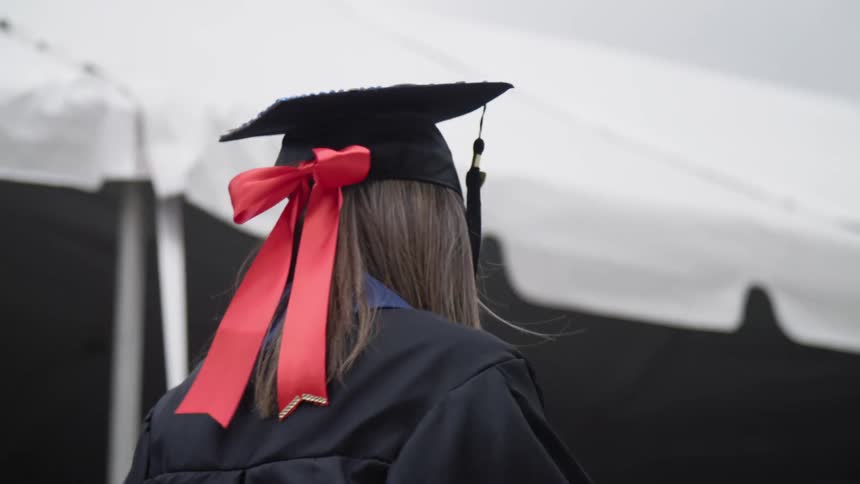 The back of a woman walking with a graduation cap on