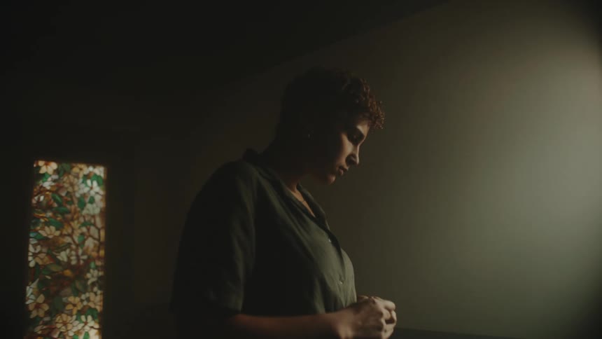 A woman starts to unbutton her shirt while pacing in a room