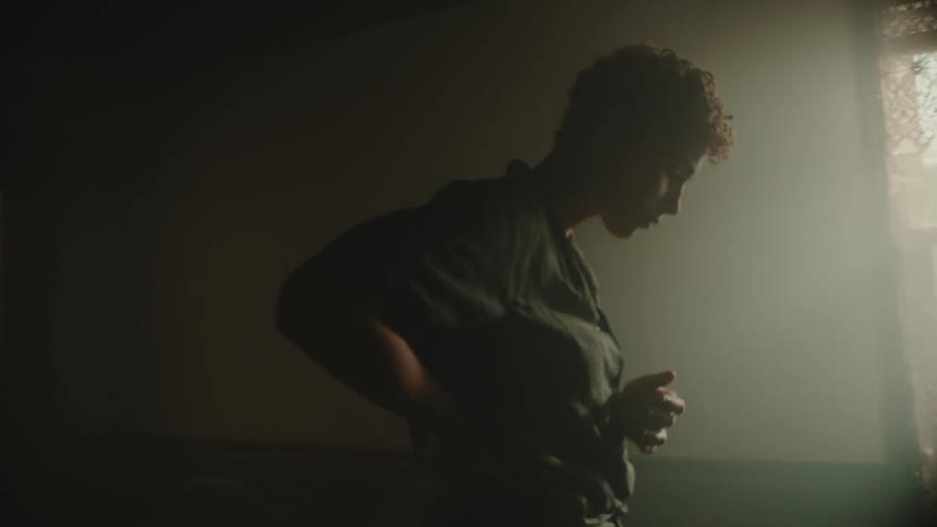 A young woman fidgets nervously in a dark room in front of a static riddled television set