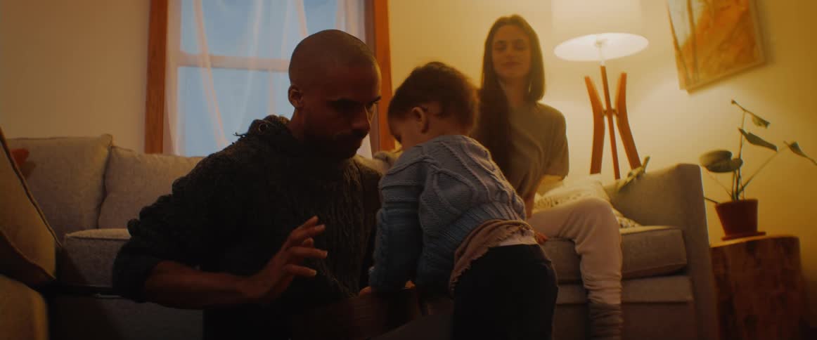 A mother and father are playing with their child in the living room of their home in the evening