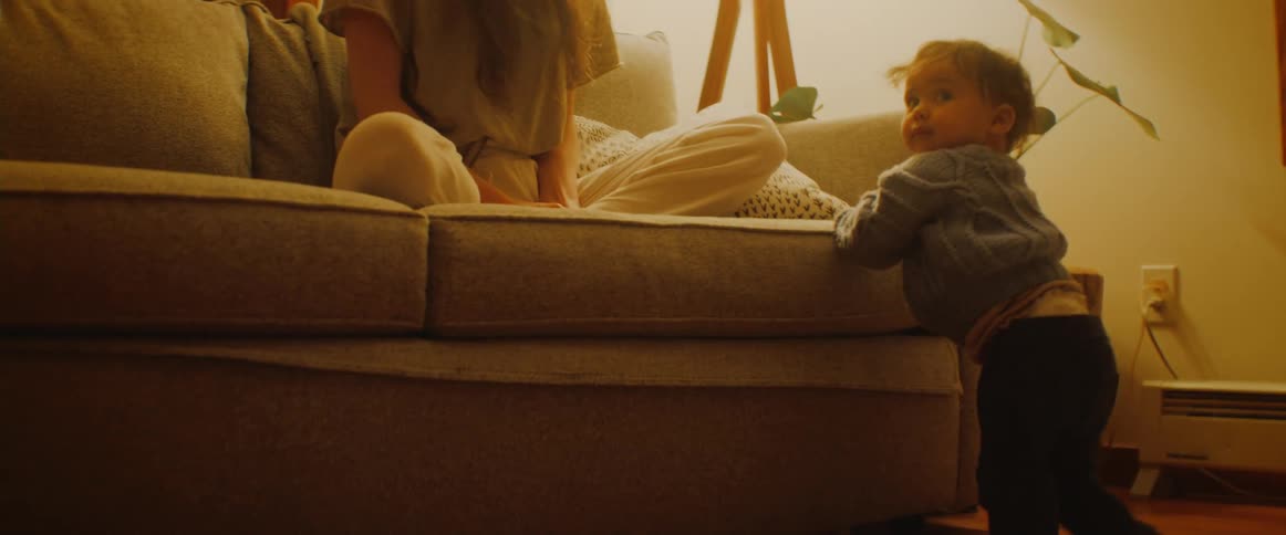 A baby crawls over to the couch