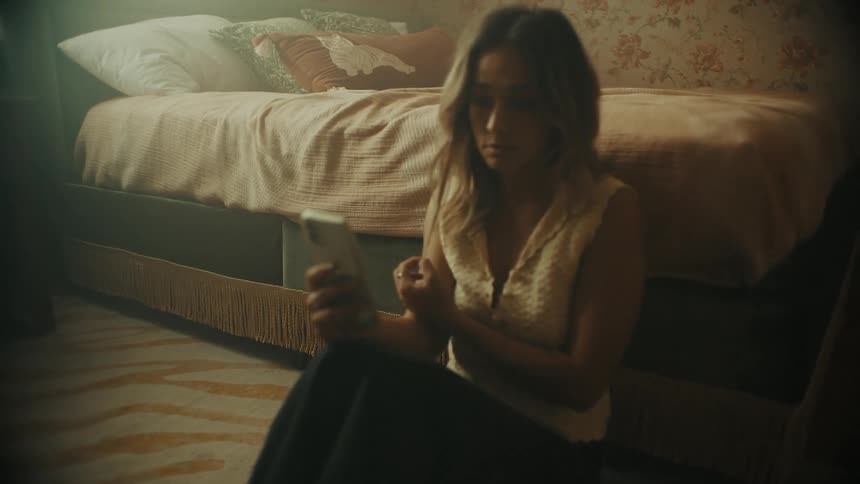 A woman sitting on the floor of her bedroom taking selfies of different head tilts and expressions