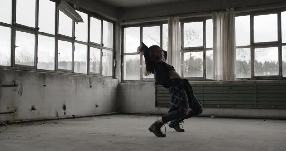 A woman does a backbend in a warehouse