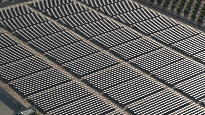 The sun is shining brightly on solar panels on a solar farm