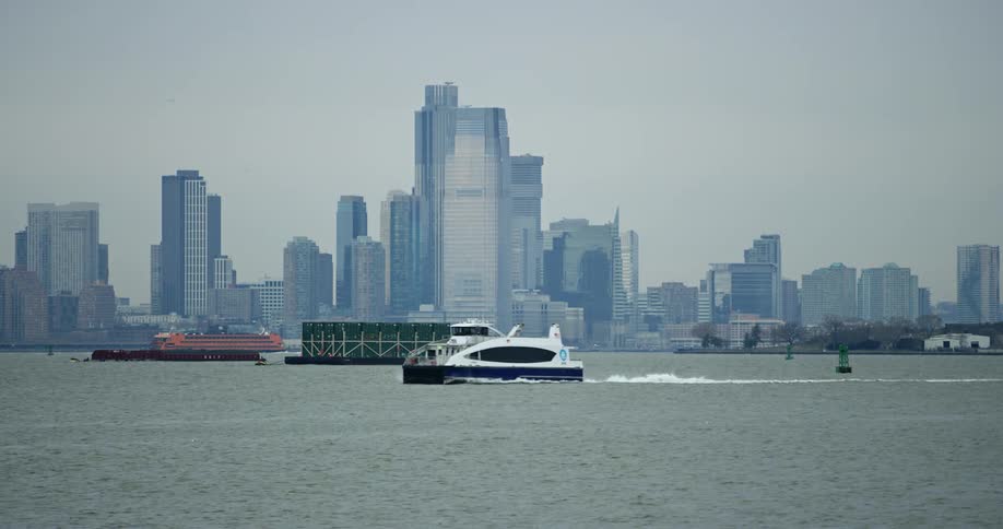 Big city skyline from a distant with skyscrapers next to sea with boats traveling