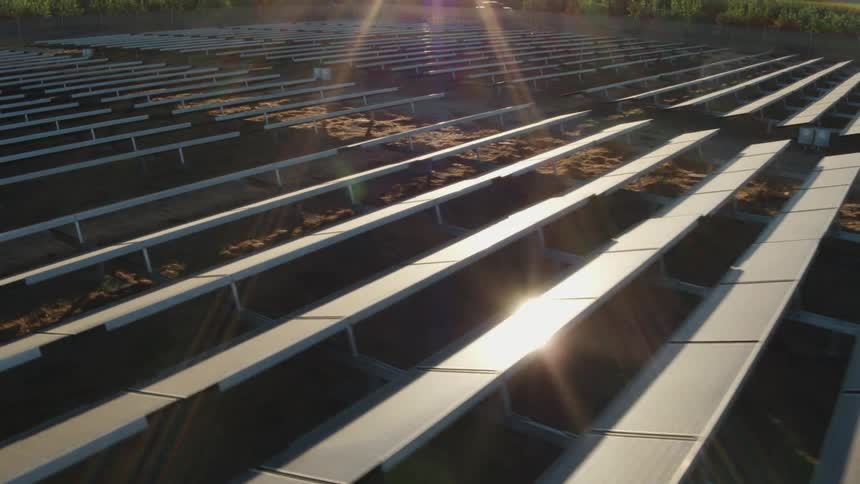 The sun is shining brightly upon solar panels in a field