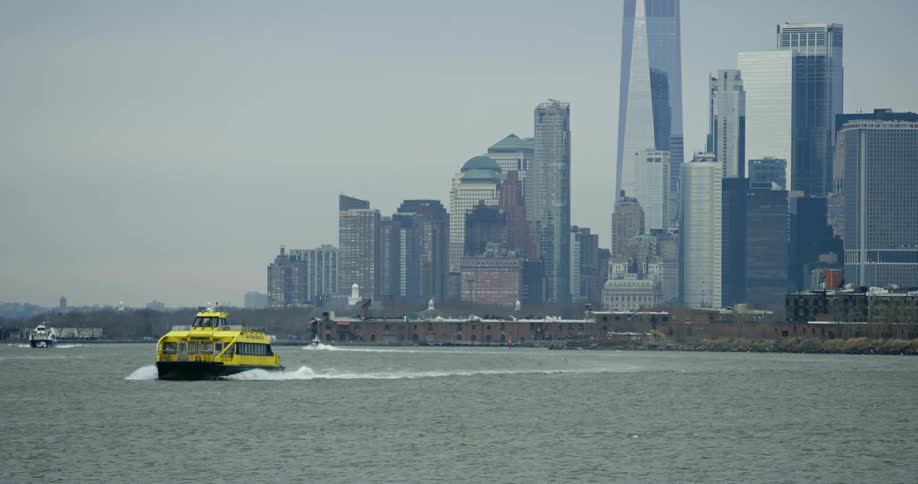 A new york water taxi leaves a wake as it travels away from the city skyline