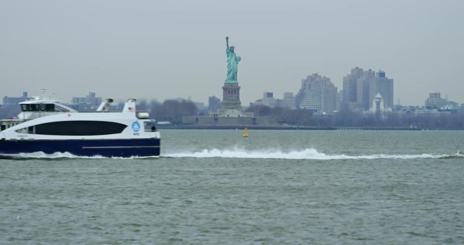 A ferry boat transporting across the harbor with statue of liberty in the background