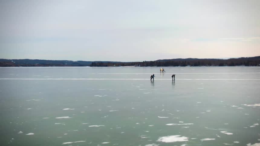 Aerial panoramic view of people ice skating on a frozen lake