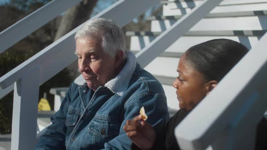 Two people eat potato chips outside