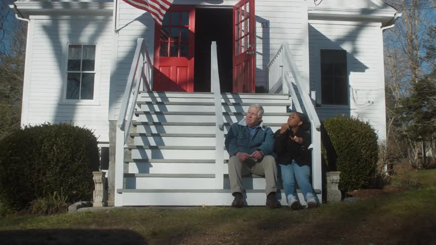 A man and woman sit on the steps of the house