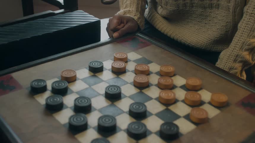 A woman laughs as she tries to figure out her next move in checkers
