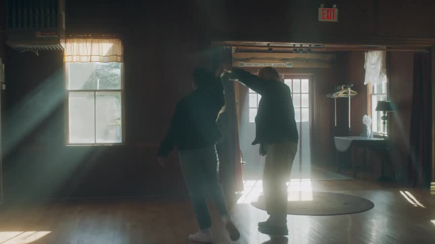 Old white man and black woman dancing together in an empty house during day time