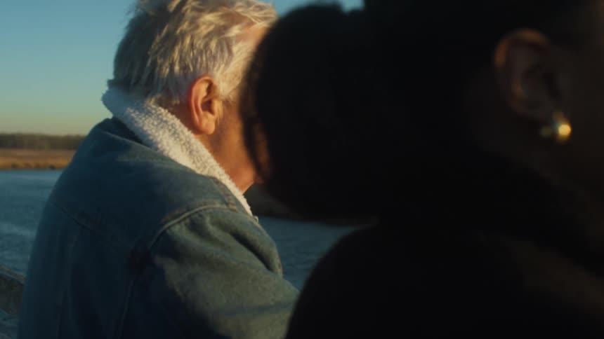 A man and woman talk by the river