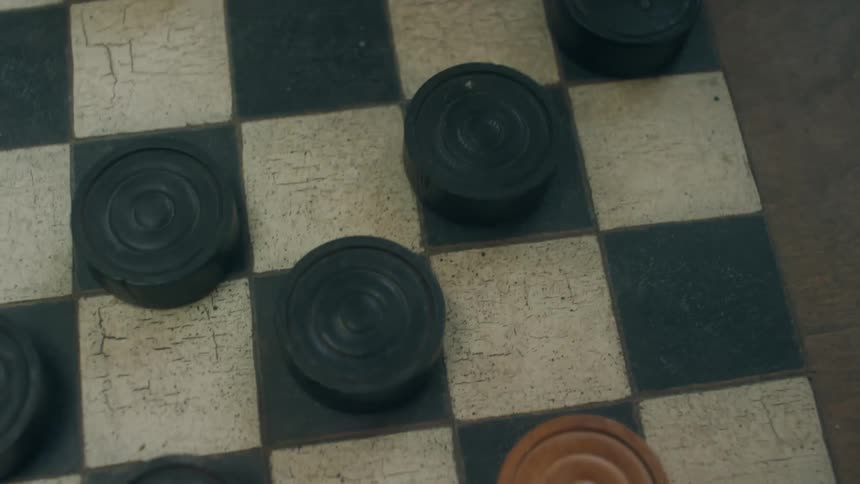 A closeup view of fingers sliding game pieces during a checkers game