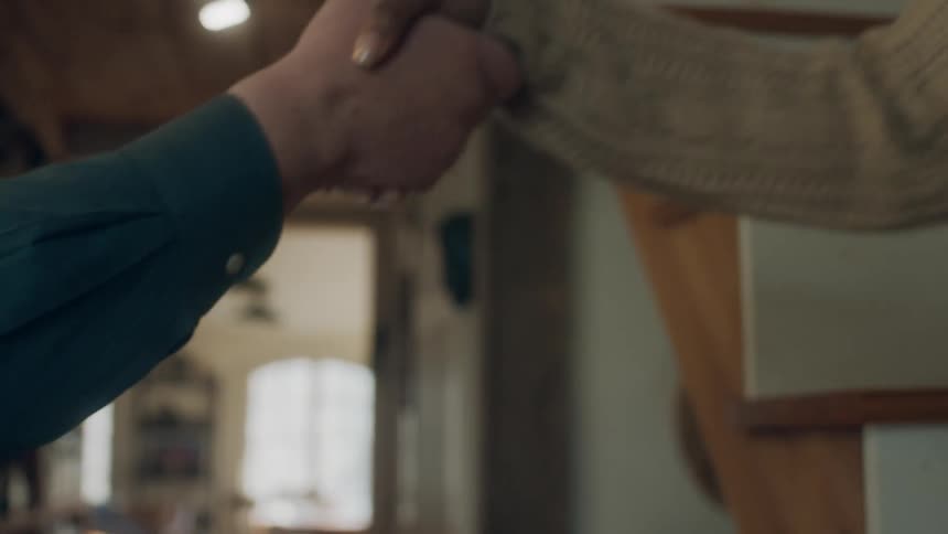 An elderly man reaches out and takes a young womans hand to help her down a stair