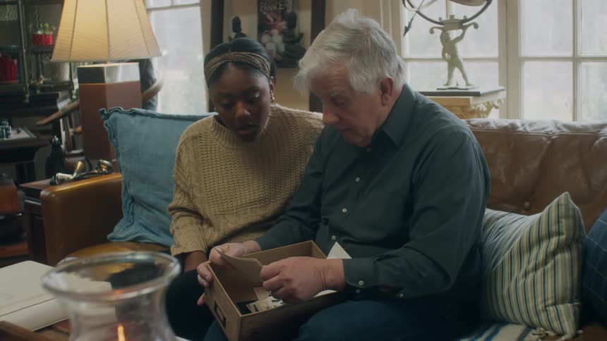 Woman sits next to man on couch as they go through photographs