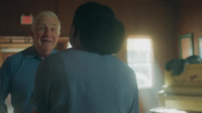 Black woman dancing talking and laughing with an old white man in the middle of an empty living room indoors
