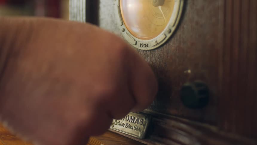 A hand turning the dial on a vintage wood clock
