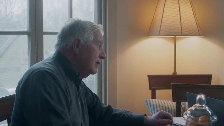 An elderly man sits and talks with a young woman at a table