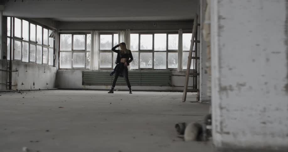 A woman dances in a dirty, windowed room