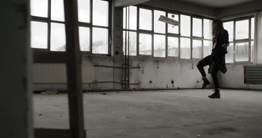 A woman in black dances in an empty room