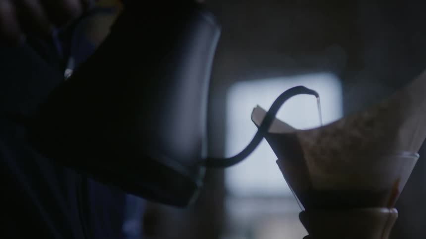 A man pours boiling water into a pour over coffee carafe