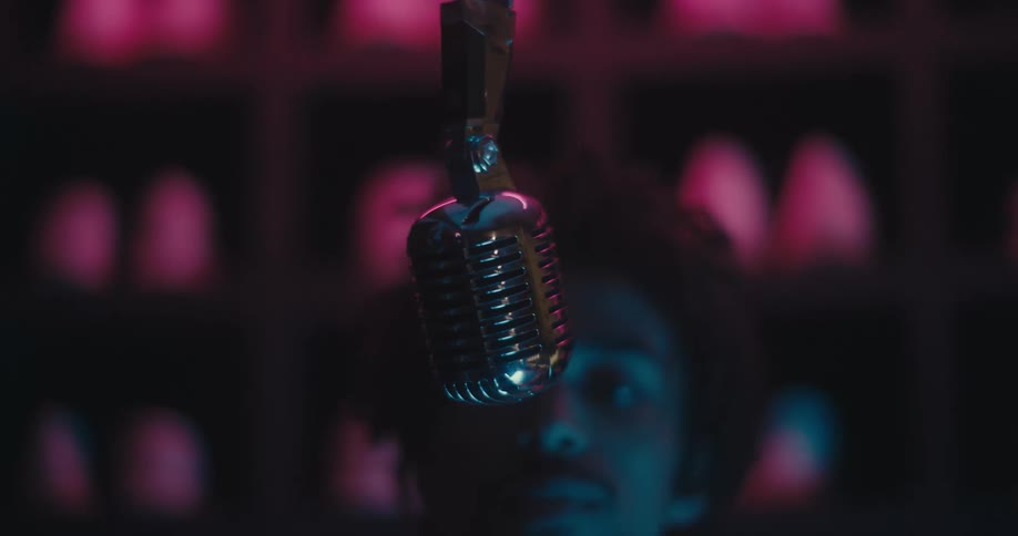 Silver microphone slowly coming down from the ceiling when a young black man grabs it