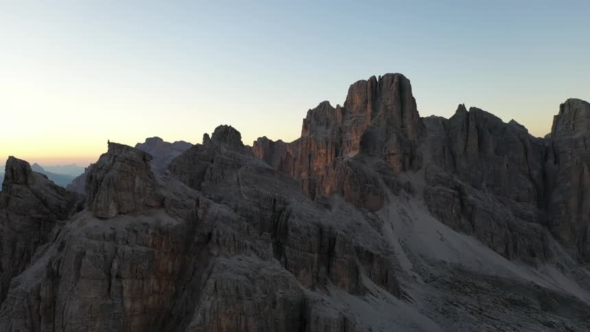 Rock formations peak high in a clear sky and mountains are in the distance