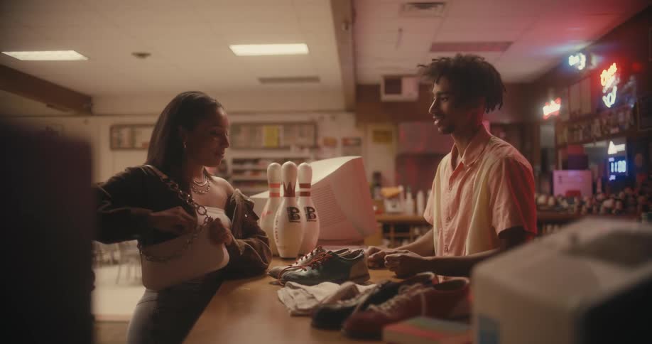 A man gives bowling shows from the counter to a woman