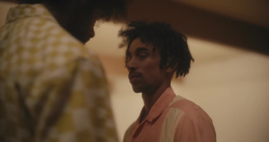 Black young man getting approached by another man in an aggresive way while a woman approaches and asks him to stop it