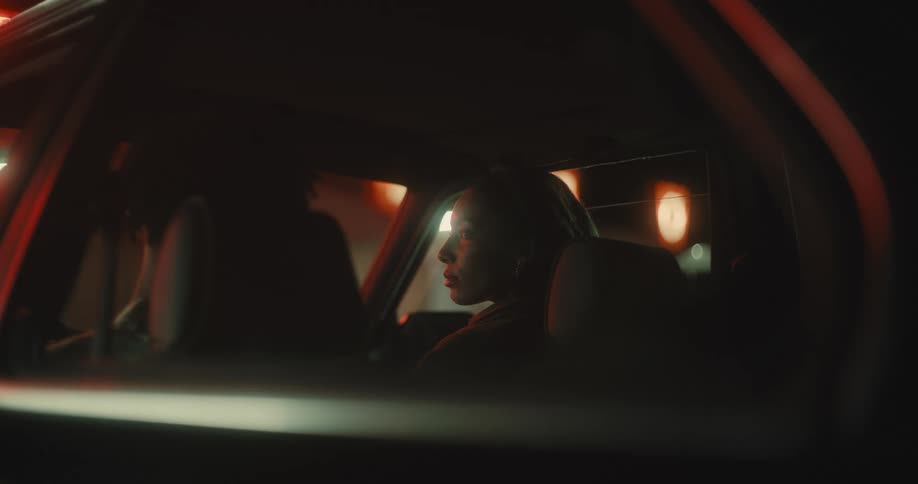 Black woman sitting at the front passenger seat of a car angrily looking at the man in the passenger seat at night