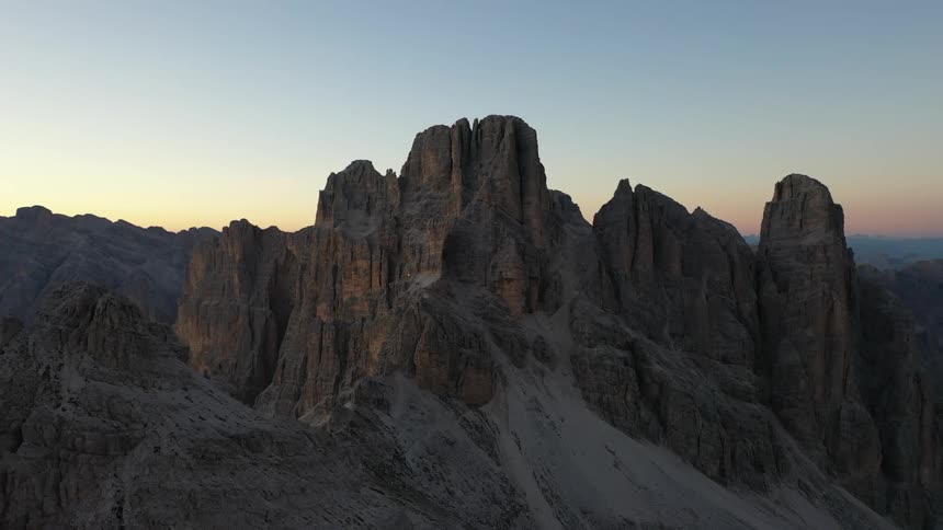 Rock formations peak high in a clear sky and mountains are in the distance