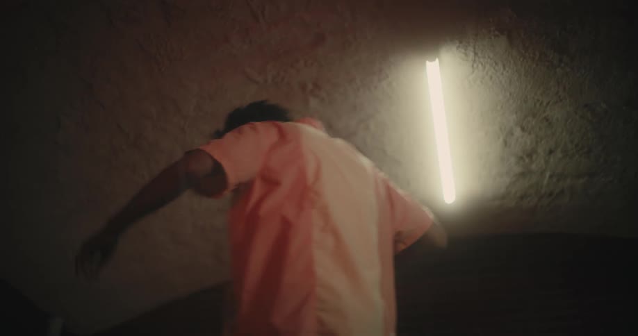 Man dances on table under fluorescent bulb
